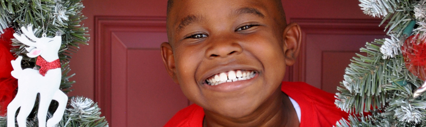 kid smiling in front of a wreath