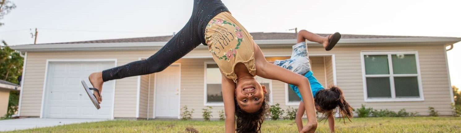 kids doing cartwheels in front of a house