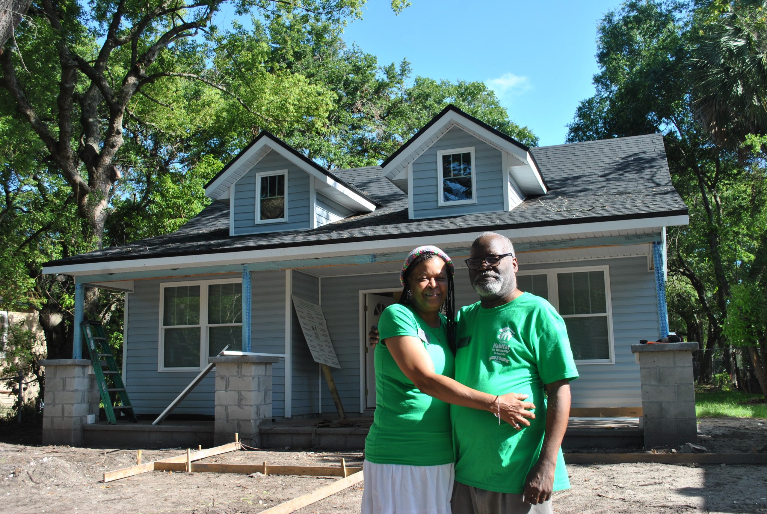 couple posing in front of a house